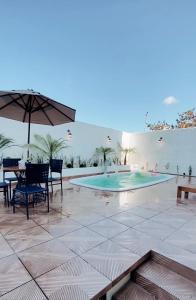 eine Terrasse mit einem Tisch, einem Sonnenschirm und einem Pool in der Unterkunft Pousada Serra Bella in Tianguá