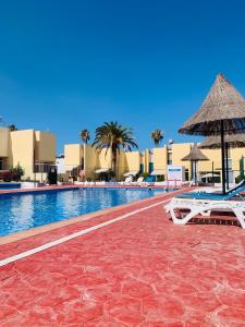a swimming pool with two lounge chairs and an umbrella at El cortijo Bungalow Playa las Americas in Playa de las Americas