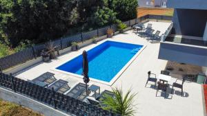 einen Blick über einen Pool mit Stühlen und einem Sonnenschirm in der Unterkunft Luxury penthouse SkyView in Trogir