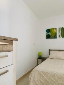 a white bedroom with a bed and a dresser at El cortijo Bungalow Playa las Americas in Playa de las Americas