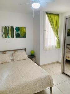 a white bedroom with a bed and a window at El cortijo Bungalow Playa las Americas in Playa de las Americas