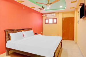 Schlafzimmer mit einem weißen Bett und orangefarbenen Wänden in der Unterkunft Flagship Veda Residency in Warangal