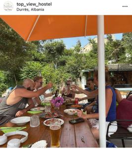 um grupo de pessoas sentadas em torno de uma mesa de madeira em Top view hostel em Durrës