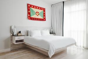 a white bedroom with a large bed and a flag on the wall at Bungalow Hotel in Long Branch