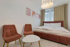 a bedroom with a bed and two chairs at LAM Pink with Jacuzzi & PS4 in Bratislava