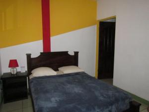 a bedroom with a bed and a red and yellow wall at Hostel Shakti in San José