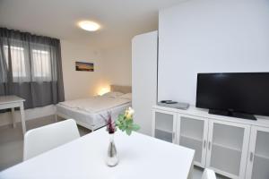 een woonkamer met een televisie en een tafel met bloemen bij Apartments Leonardo in Primošten