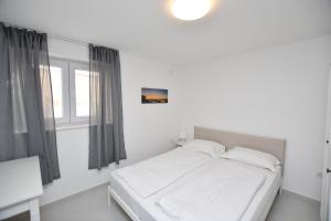 een wit bed in een kamer met een raam bij Apartments Leonardo in Primošten