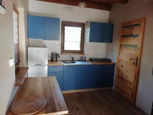 a kitchen with blue cabinets and a wooden table at Domek Smerfna Chatka in Wąglikowice