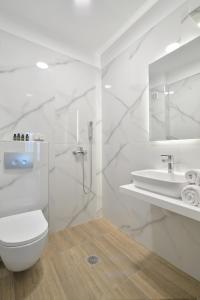 a white bathroom with a toilet and a sink at Niel Holiday Apartments, Panel Hospitality Homes & Villas in Leptokaria