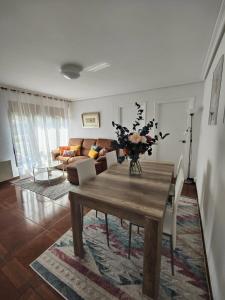 una sala de estar con una mesa de madera y un jarrón de flores en La Casuca De Mabel, en Revilla de Camargo