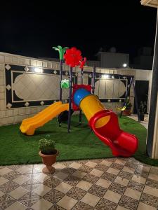 un parque infantil con un tobogán en el césped por la noche en فيلا ميسرة الهدا, en Al Hada