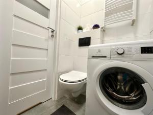 ein Badezimmer mit einer Waschmaschine und einem WC in der Unterkunft MMRent Jungle Room in Danzig