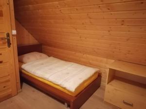 a small room with a bed in a wooden room at Domek Smerfna Chatka in Wąglikowice