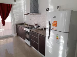 a kitchen with a white refrigerator and a stove at Hermoso departamento. Todo equipado. Zona norte in Puerto Madryn