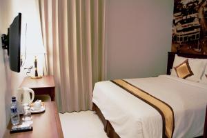 a hotel room with a bed and a desk and a bed sidx sidx at Varna Culture Hotel Soerabaia in Surabaya