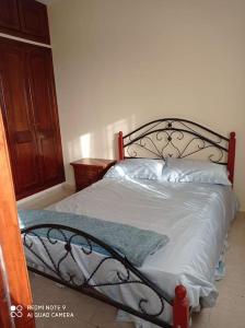 um quarto com uma cama preta com lençóis e almofadas brancos em Grand appartement à deux pas de la plage em Souira Guedima