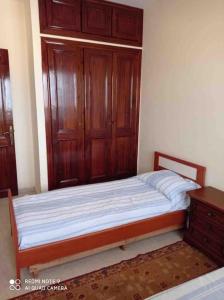 um quarto com uma cama com armários de madeira e uma cómoda em Grand appartement à deux pas de la plage em Souira Guedima