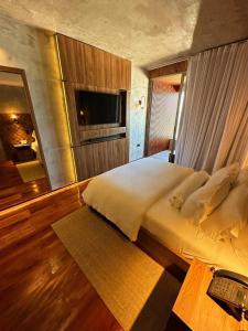 a bedroom with a bed with a television and a desk at Duke Beach Hotel Maresias in Maresias