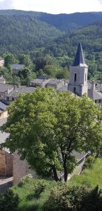 uma árvore em frente a um edifício com uma igreja em Maison proche de la nature em Quérigut