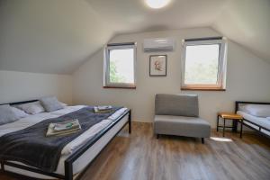 a bedroom with two beds and a chair and two windows at Sklep 353 in Velké Bílovice