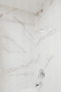a shower with white marble walls and chrome fixtures at Sandston Inn in Sandston
