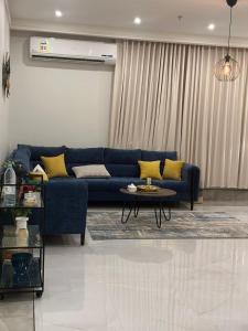 Family Furnished Apartment in Khobar في الخبر: غرفة معيشة مع أريكة زرقاء وطاولة