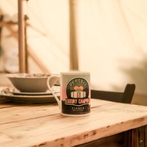 PenuwchTinker the Bell Tent at Pentref Luxury Camping的坐在木桌边的咖啡杯