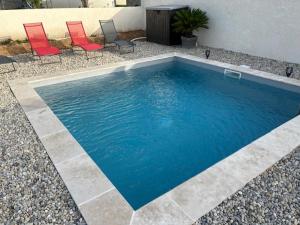 a swimming pool with two chairs and a table at vacances en Ardéche "maison Chauvet" in Vallon-Pont-dʼArc