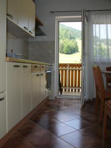 eine Küche mit weißen Schränken und Blick auf eine Veranda in der Unterkunft Apartments Rožič in Kranjska Gora