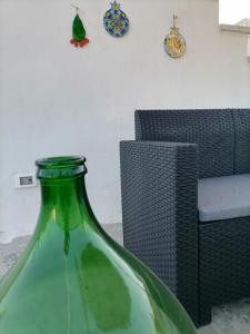 a green glass vase sitting in front of a chair at AREMU in Lecce