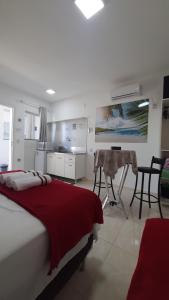 a bedroom with a bed and a table and a kitchen at Pousada APART PenhaFlat- Studio a 700 mts do parque in Penha