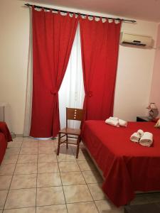 カターニアにあるB&B Casa Valeriaの赤いカーテンと椅子が備わる客室のベッド2台