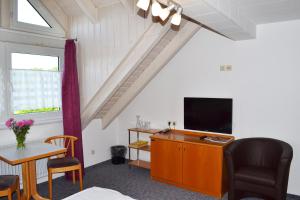 a living room with a television and a table with a chair at Hotel Relax in Singen