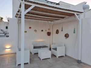 une pergola blanche avec des meubles blancs sur une terrasse dans l'établissement Le Terrazze di Scirocco, à Gallipoli