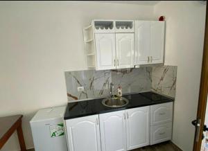 eine kleine Küche mit weißen Schränken und einem Waschbecken in der Unterkunft Arlind's Apartaments in Vlorë