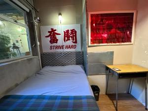 Bett in einem Zimmer mit Schild an der Wand in der Unterkunft Wontonmeen in Hongkong