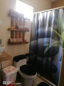 a bathroom with a toilet and a shower curtain at Casa Noria in Tepic