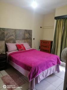 ein Schlafzimmer mit einem Bett mit einer lila Decke in der Unterkunft Casa Noria in Tepic