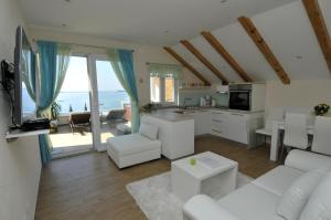 una sala de estar con muebles blancos y vistas al océano. en Casa Milolaza, en Mlini