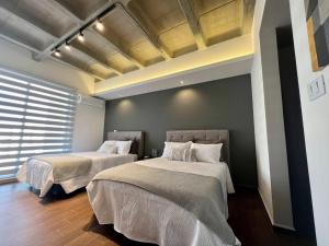 2 camas en una habitación con 2 ventanas en Departamento Polanco Agora 10, en San Luis Potosí