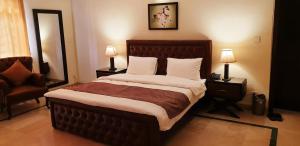 a bedroom with a large bed with two lamps and a chair at Reina Boutique Hotel - G6 in Islamabad