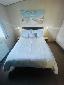 una camera da letto con un grande letto con lenzuola e cuscini bianchi di Summer Breeze-Hoburne Cotswolds a South Cerney