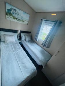 two beds in a small room with a window at Summer Breeze-Hoburne Cotswolds in South Cerney