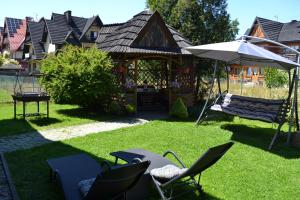 podwórko z krzesłami i parasolem oraz niektóre domy w obiekcie PERŁA w mieście Białka Tatrzanska