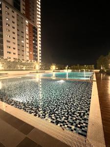 a swimming pool at night with two tall buildings at High Flyer KLIA at Alanis Residence Kota Warisan in Sepang