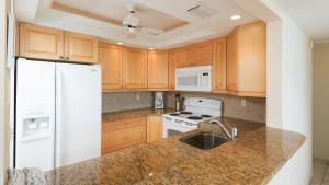 uma cozinha com armários de madeira e um frigorífico branco em 6415 Midnight Pass #902 em Siesta Key