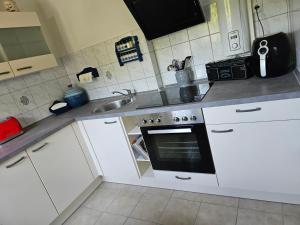 uma cozinha com armários brancos, um lavatório e um forno em Ferienwohnung 1 Am Park em Divitz