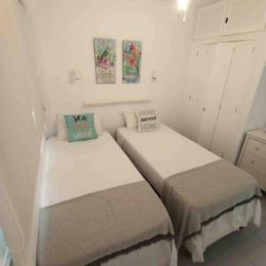 マスパロマスにあるBungalow Maspalomasの白い壁の小さな部屋のベッド2台