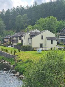 a large white house sitting next to a river at Lakeland Village in Newby Bridge